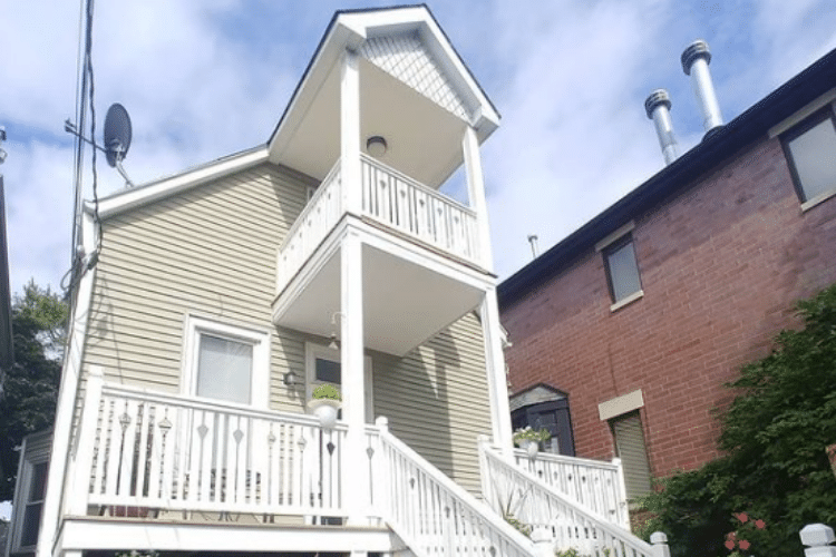 Two-story house with white railings on balconies and stairs, conforming to safety codes with a clear path for egress.