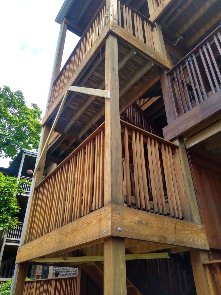 Close-up of a multi-story wooden balcony structure with robust railings and beams in Chicago.