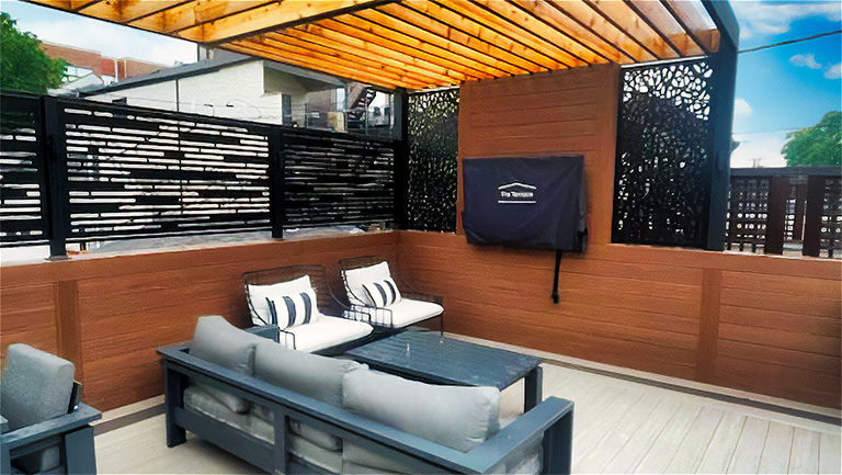 Outdoor patio area with modern furniture, decorative privacy screens, and a wooden pergola overhead.