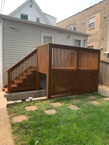 Wooden backyard deck with vertical slat railings providing privacy, connected to a house with a stone pathway leading to it.-porch without roof