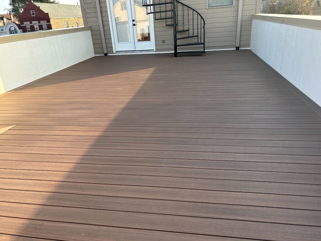 Spacious rooftop deck with composite wood flooring and high privacy walls in an urban setting, casting soft shadows in the evening light.
