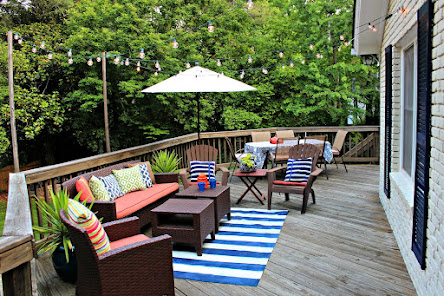 Rustic yet modern deck space with an array of seating options adorned with multi-colored cushions, under the ambiance of warm, twinkling lights.