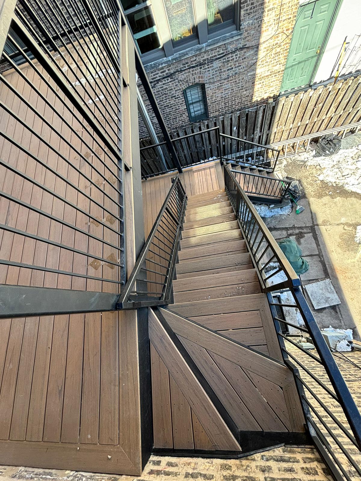 Modern wood and metal outdoor stairs leading down to a backyard.