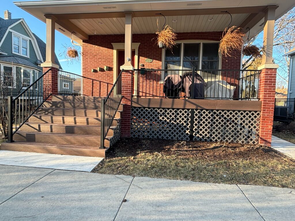 Spacious wooden porch with black metal railings and lattice enclosure, leading to a red brick house. Features hanging planters and covered outdoor furniture. Ideal example of stylish Chicago porch architecture.







