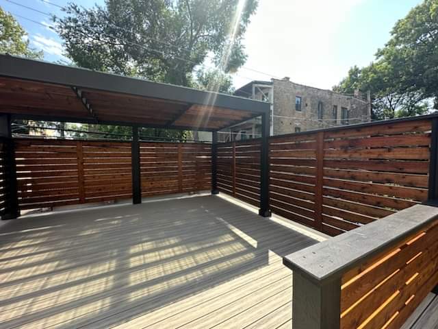 Modern rooftop deck with horizontal wood privacy slats and a black steel pergola structure