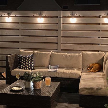 Evening ambiance on a deck with string lights, plush seating, and a sleeping cat.